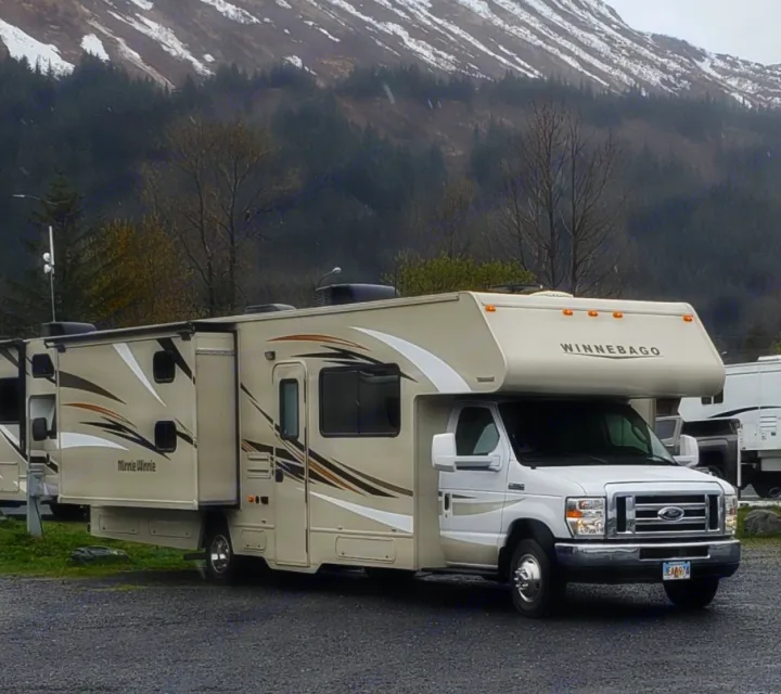 RV rental: Tan Winnebago Minnie Winnie motorhome with slide-out, parked in a scenic mountain setting.. Winnebago Minnie Winnie 2017