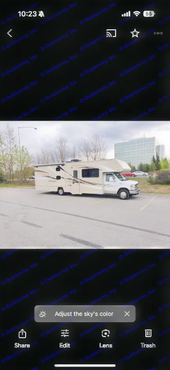 Light tan Class C RV rental parked in a lot on a cloudy day. Trees and a modern building are in the background, perfect for travel.. Winnebago Minnie Winnie 2017