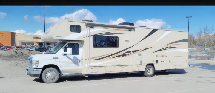 A beige Minnie Winnie RV rental awaits adventure in a store parking lot.. Winnebago Minnie Winnie 2017