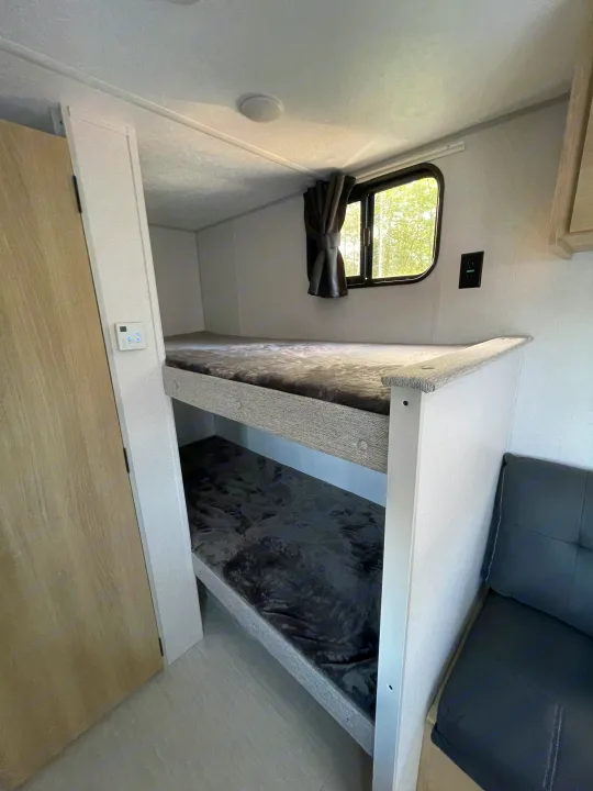 Bright RV rental interior with cozy bunk beds, a window, and comfortable seating for your next adventure.. Forest River Salem 2024
