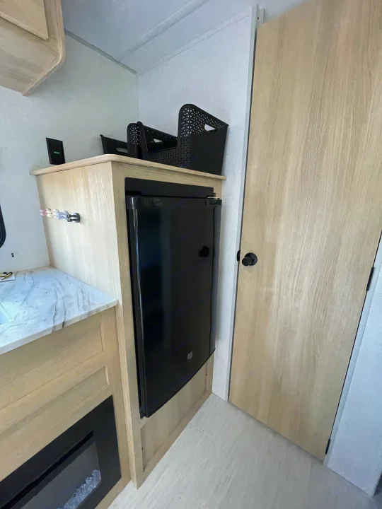 RV rental: Bright interior featuring light wood cabinetry, built-in mini-fridge, storage baskets, and a door.. Forest River Salem 2024