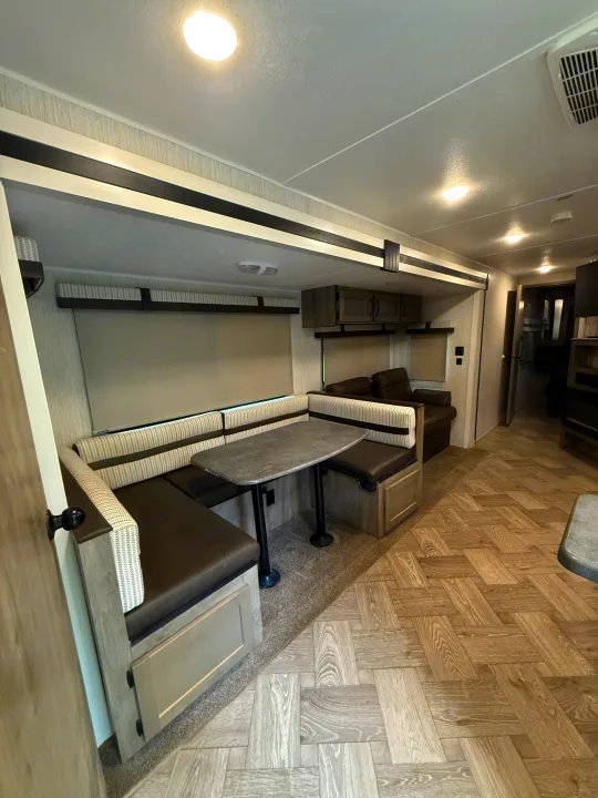Dinette and living area inside a modern RV rental, featuring comfortable seating, a table, and light wood-look flooring.. Forest River Palomino Puma 2022
