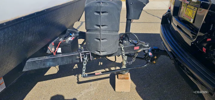RV rental ready: Trailer hitch connection with battery, propane tanks, and weight distribution system linked to SUV.. Keystone RV Bullet Crossfire 2021