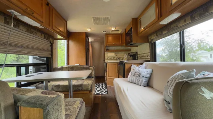 Spacious RV rental interior with a dining booth, kitchen, and cozy sofa for comfortable road trips.. Tioga FTWD 2004
