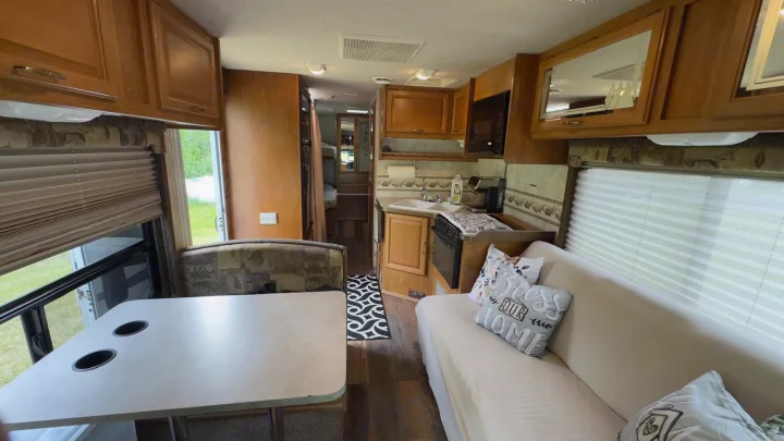 Explore this cozy rv rental interior. Features a full kitchen, dining booth, and comfortable sofa bed.. Tioga FTWD 2004
