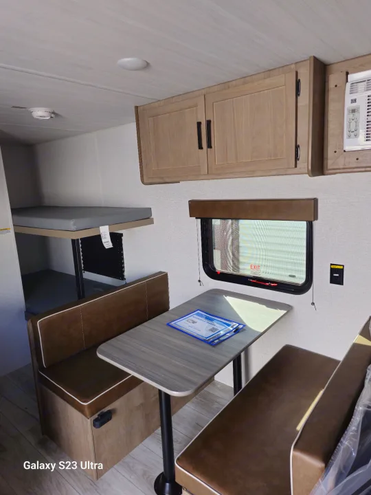 Interior of an RV rental with a dinette, bunk beds, and overhead cabinets, offering functional living amenities.. Keystone RV Springdale 2025