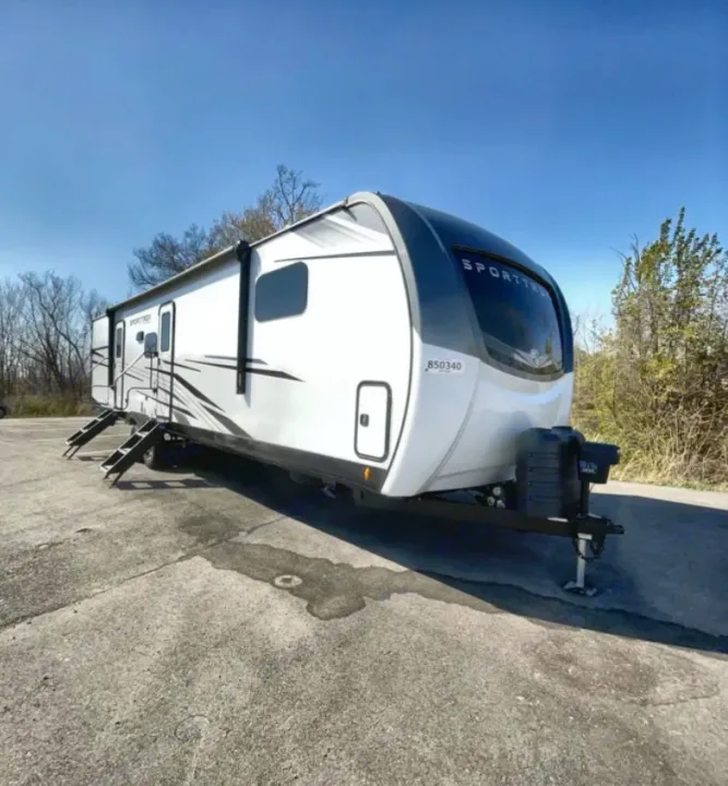 White RV travel trailer with steps extended, parked on paved lot. Explore the outdoors with this spacious rv rental.. Venture Rv SPORTTREK TOURING EDITION 2025