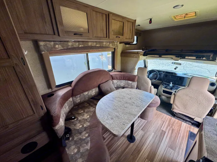 Comfortable RV rental interior featuring a dinette, overhead bunk, and cockpit area. Ideal camper for your next adventure.. Coachmen Freelander 21QB 2016