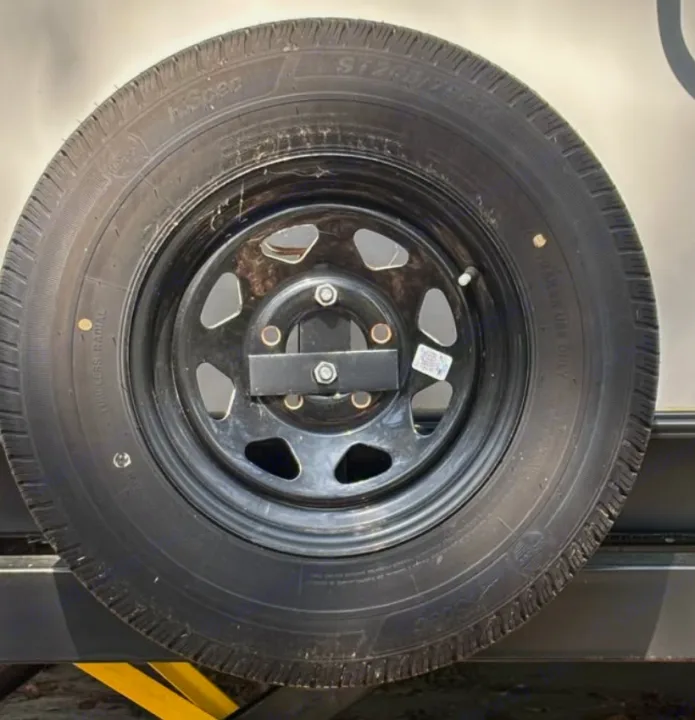 An RV rental's black spare tire, with a visible "trailer use only" label, securely mounted on a black wheel.. Crossroads RV Sunset Trail Super Lite 2022