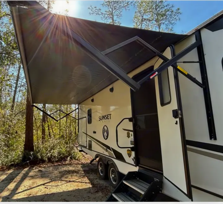 Sunny day at the campsite! An inviting Sunset Trail rv rental travel trailer with its awning extended, ready for outdoor fun.. Crossroads RV Sunset Trail Super Lite 2022
