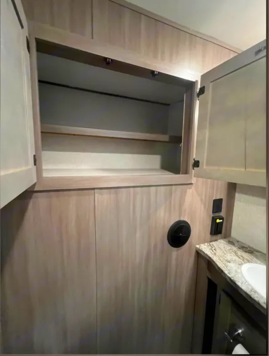 RV rental: Open cabinet with shelves, compact bathroom vanity, and wall vent, showing ample storage in a compact space.. Crossroads RV Sunset Trail Super Lite 2022