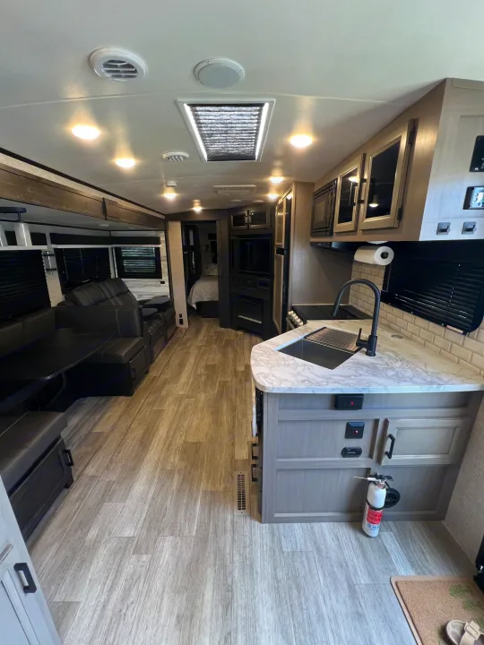 Spacious, modern RV rental interior featuring a comfortable living area, full kitchen, and a glimpse of the bedroom.. Jayco White Hawk 2022