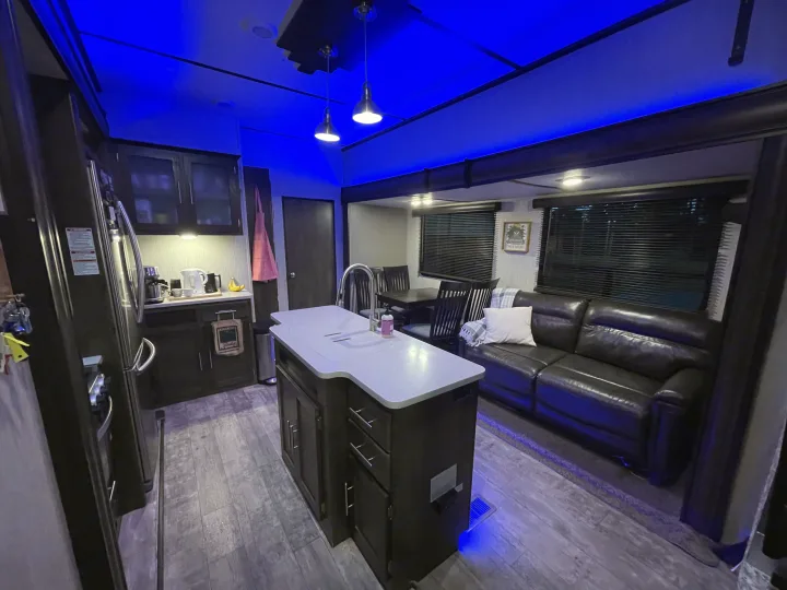 Spacious RV rental interior featuring a full kitchen, living area with sofa, dining space, and atmospheric blue lighting.. Crossroads RV Volante 2020