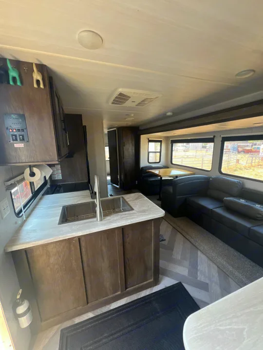Modern RV rental interior with spacious kitchen, comfortable living/dining area, and large windows.. Forest River Wildwood 2020