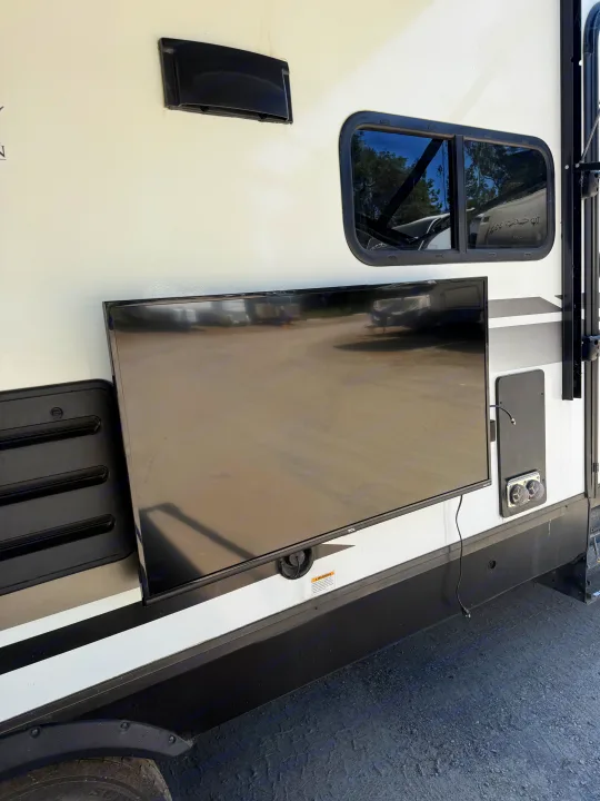 RV rental exterior featuring a mounted outdoor TV, ready for camping entertainment with accessible utility ports.. Grand Design Imagine 2021