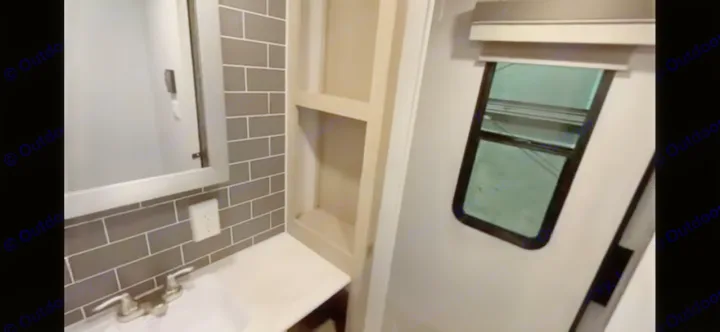 Modern RV rental bathroom: compact design with vanity, mirror, gray tiled backsplash, built-in shelves, and window.. Forest River Salem View 2024