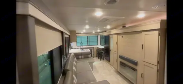 Modern RV rental interior: spacious living/kitchen area with cozy seating, bright windows, and built-in storage.. Forest River Salem View 2024