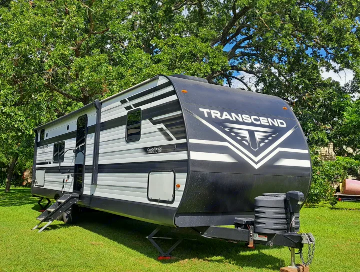 Spacious Grand Design Transcend RV rental parked on green grass under large trees, ready for your next adventure.. Grand Design Transcend Xplor 2024