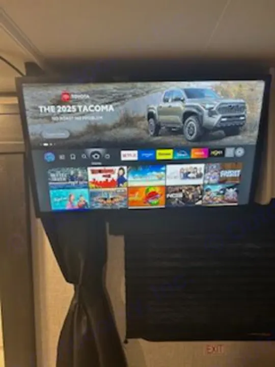 RV rental's TV displaying a 2025 Toyota Tacoma ad and streaming services, offering entertainment on the road.. Jayco Jay Flight SLX 2024