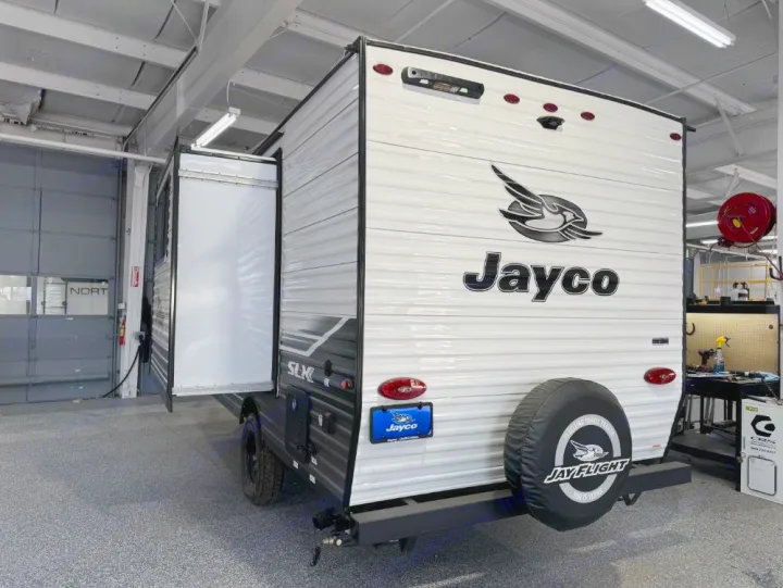 White Jayco travel trailer with slide-out extended, perfect for your next RV rental adventure. Seen in a service bay.. Jayco Jay Flight SLX 2024