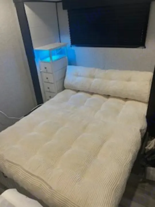 Cozy RV rental bedroom with a comfy padded bed, blue LED lighting on storage, and a dark window blind.. Jayco Jay Flight SLX 2024