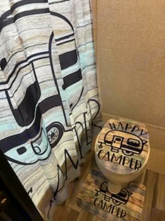 This RV rental bathroom boasts a fun "Happy Camper" theme with a matching shower curtain, toilet lid, and floor mat.. Jayco Jay Flight SLX 2024