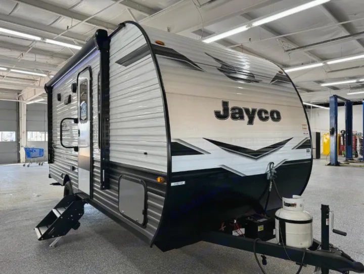 New Jayco travel trailer, ready for adventure! This RV rental option is shown indoors, with its awning and steps extended.. Jayco Jay Flight SLX 2024