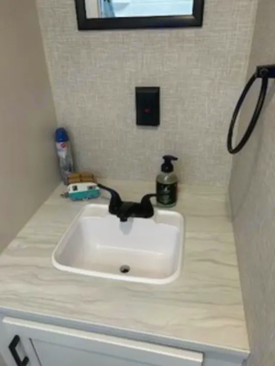 RV rental bathroom with compact sink, black faucet, soap dispenser, and towel ring on textured wall.. Jayco Jay Flight SLX 2024