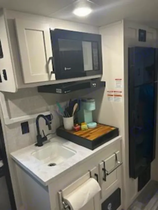 Inside an RV rental kitchen: a compact galley with microwave, sink, coffee station, and refrigerator.. Jayco Jay Flight SLX 2024