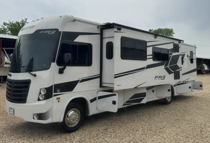 White Forest River FR3 RV rental, a Class A motorhome with extended slide-out & open storage, parked on gravel.. FR3 FR3 Motorhome 2022