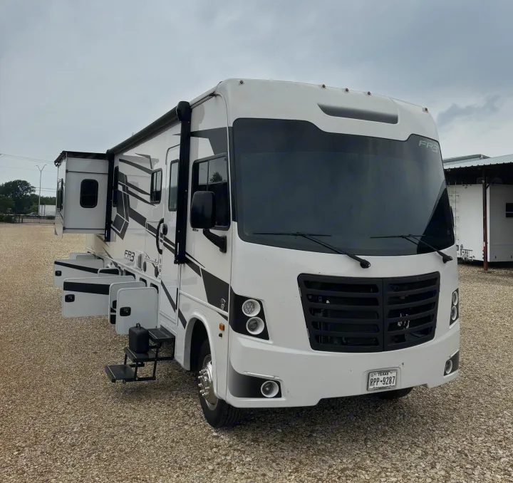 A white Forest River FR3 RV rental, with side slide-outs and storage open, parked on gravel under an overcast sky.. FR3 FR3 Motorhome 2022