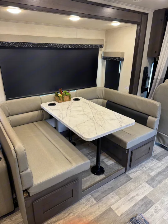 Spacious RV rental dinette featuring U-shaped booth seating, a marble-look table, and dark privacy blinds.. FR3 FR3 Motorhome 2022