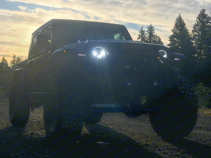 Silhouetted off-road vehicle, bright lights cutting through dusk. Great for exploring remote areas before returning to your RV rental.. Dodge Jeep Unlimited X 4x4 2021