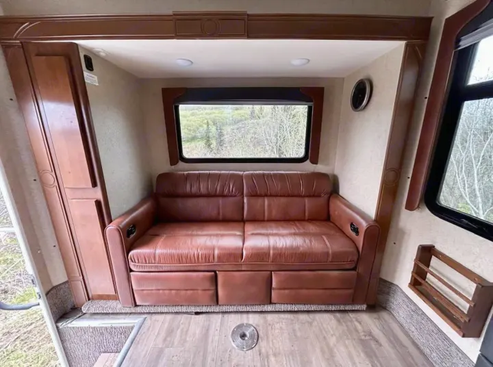 RV rental's inviting living area features a plush brown sofa and scenic window views. Perfect for your next adventure.. Lance 1172 2017