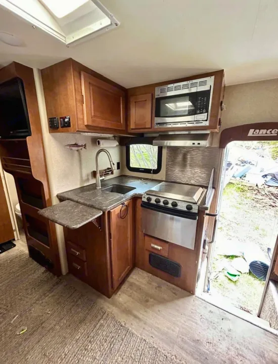 Explore this RV rental's compact kitchen with a sink, stove, microwave, and fold-out counter for efficient space use.. Lance 1172 2017