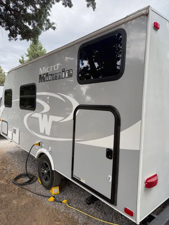 Side view of a grey Winnebago Micro Minnie RV rental, with power hookup and exterior compartments visible.. Minnie Micro Minnie 2017