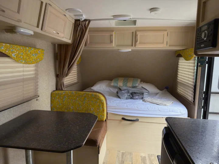 An rv rental's organized interior features a bed, dinette, and ample storage in overhead cabinets, ready for adventure.. Minnie Micro Minnie 2017