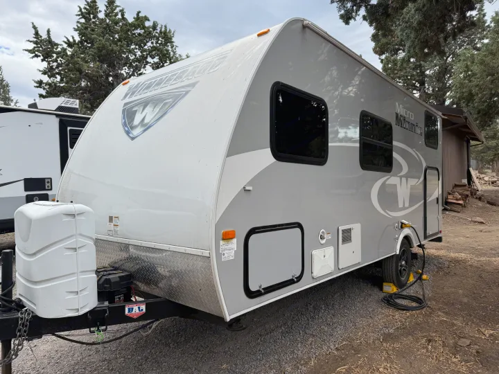 Winnebago Micro Minnie RV rental parked outdoors, showing its grey and white exterior and propane tank.. Minnie Micro Minnie 2017