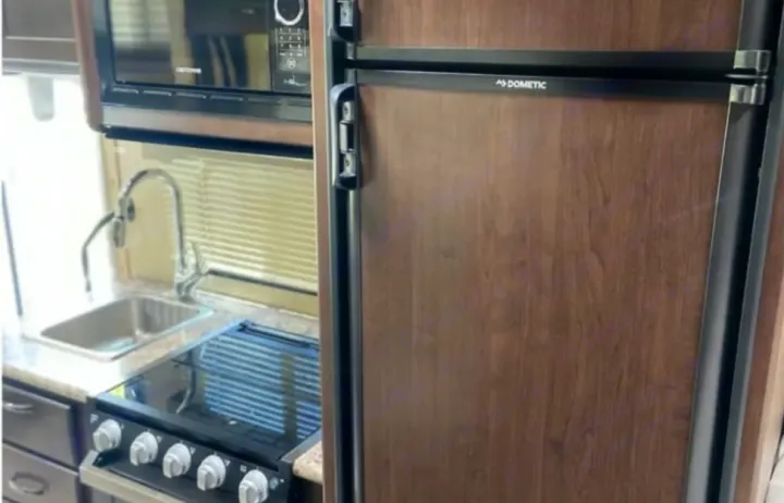 RV rental kitchen shows a Dometic refrigerator, microwave, stove, and sink for convenient travel.. Coachmen Freedom Elite 2019