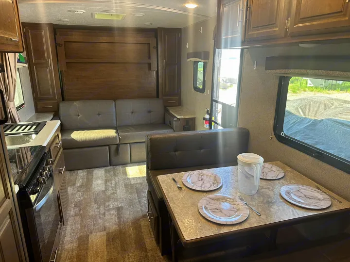 Spacious RV rental interior with a multi-purpose living area: convertible couch/bed, dining booth, and full kitchen.. Forest River Rockwood Mini Lite 2020