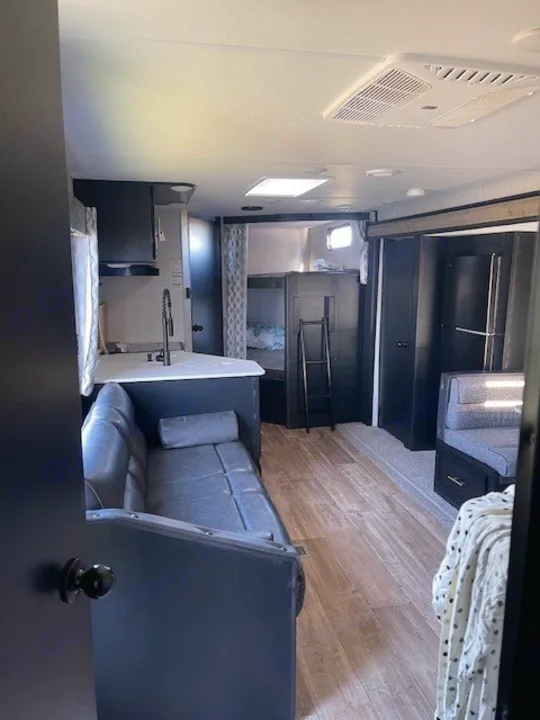 Inside our cozy RV rental: living room sofa, kitchen, and bunk beds. Ideal travel trailer for your getaway.. Forest River Cherokee 2022