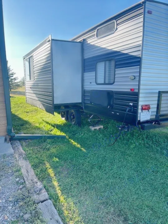 Exterior view of an RV rental travel trailer with its slide-out extended, parked on a sunny, grassy spot.. Forest River Cherokee 2022
