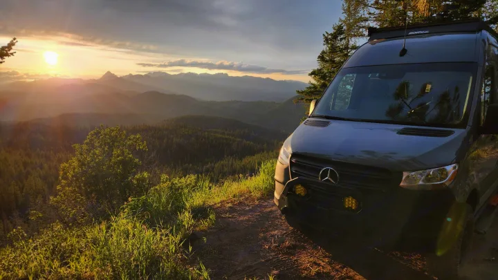 Scenic sunset from a mountain overlook with a Mercedes Sprinter RV rental. Golden light bathes forests and distant peaks.. Mercedes-Benz Sprinter 2022