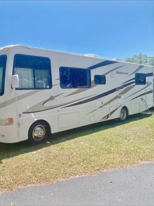 A white Hurricane RV motorhome, ideal for rv rental, is shown parked on green grass under a clear blue sky.. Hurricane F53 2010