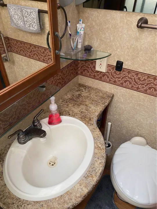 RV rental bathroom with sink, mirror, toilet, and toiletries. Compact and functional, ready for your travels.. Hurricane F53 2010