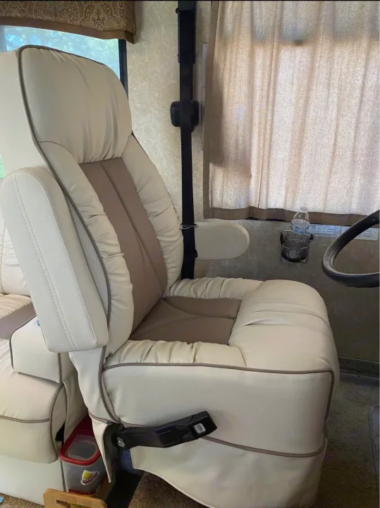 Spacious driver's seat of an RV rental, featuring two-tone upholstery and window curtains for comfortable travel.. Hurricane F53 2010