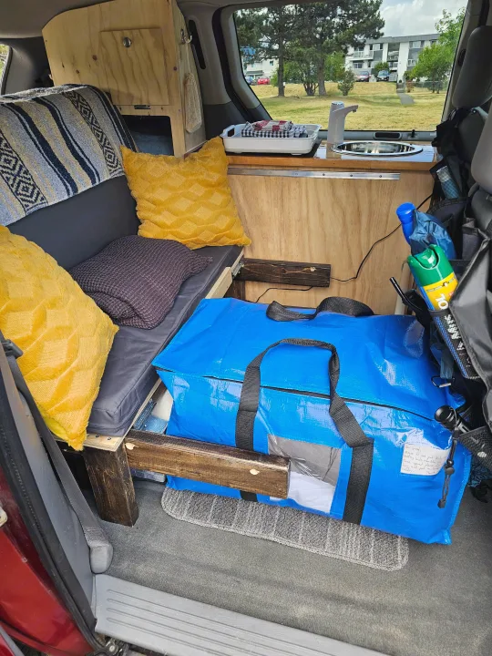 Cozy RV rental interior with bed, sink, and clever storage solutions, perfect for compact travel.. Dodge Caravan 2006
