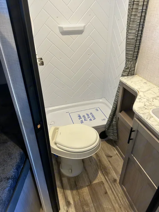 RV rental interior showcasing bunk beds, a TV, and counter. This compact space offers comfortable living for travelers.. Coleman Dutchman Light 2023