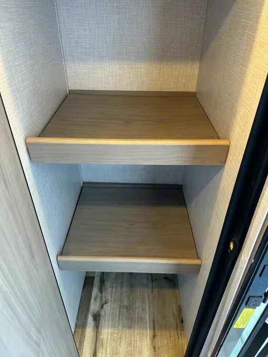 This RV rental features a clean, organized storage closet with two light wood-grain shelves, ideal for trips.. Coleman Dutchman Light 2023