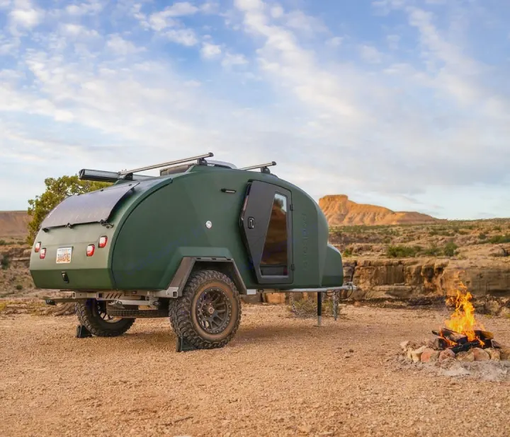An off-grid escapod teardrop trailer (rv rental) with solar panels and off-road tires, camped in the desert with a fire pit.. Escapod Topo 2 2024